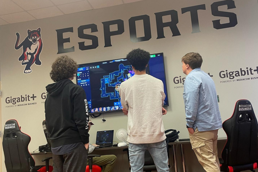 Students watching a video game on a monitor on the wall in the esports gaming room