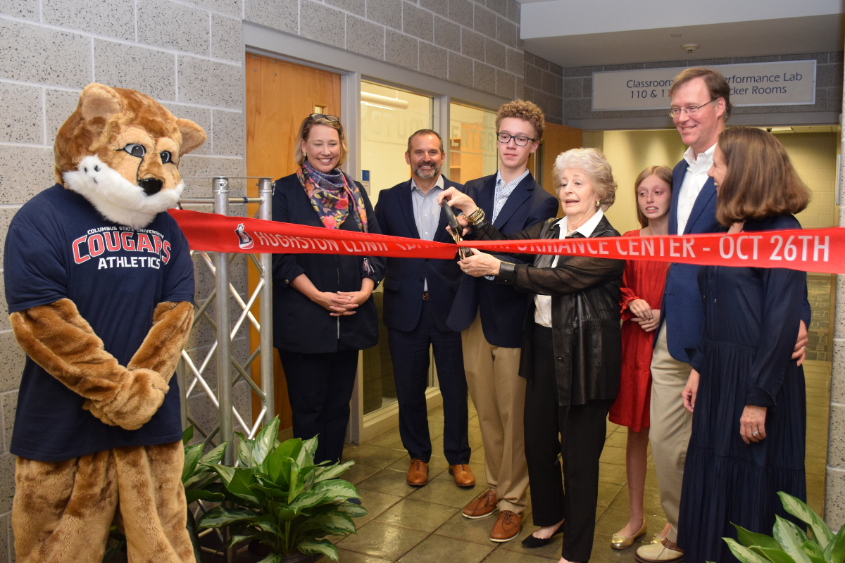 A group of people and Cody the Cougar mascot cutting a grand-opening ribbon