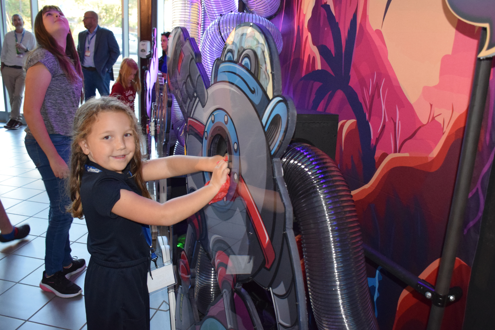 Picture of a girl putting her hand into the opening of an alien robot display character