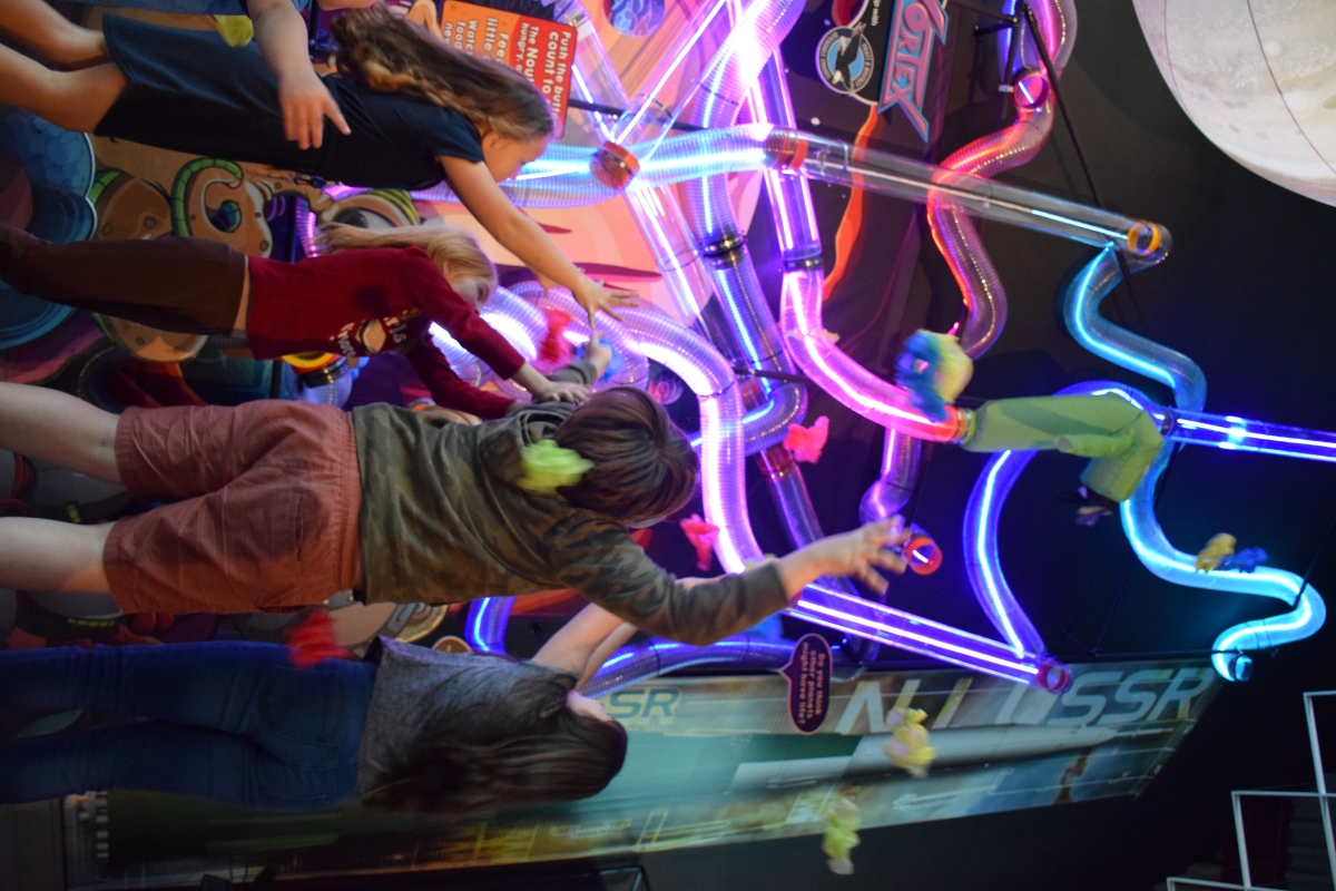 Kids catching colorful cloth items being ejected from the Guzzle Vortex exhibit