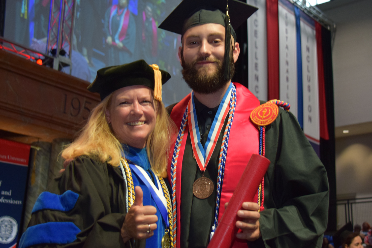 Dean Cindy Ticknor standing with a graduating student at a graduation ceremony