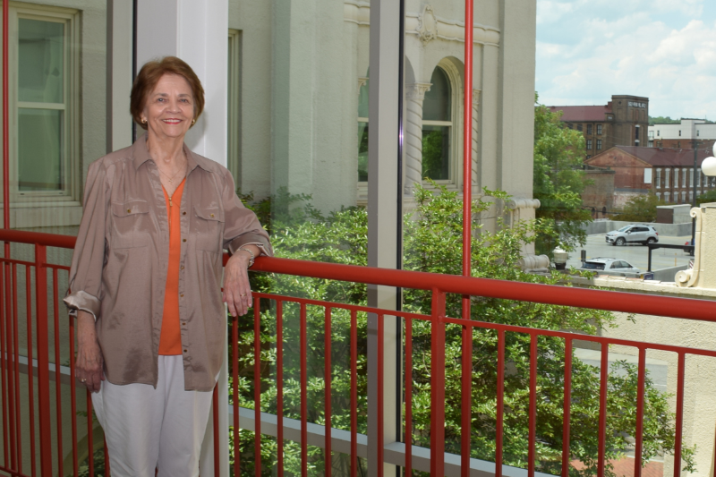 Ellen Roberts standing alongside a railing in front of a window.