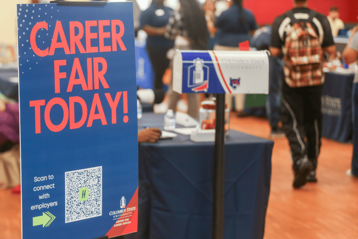 "Career Fair Today" poster in the foreground with career fair tables in the background