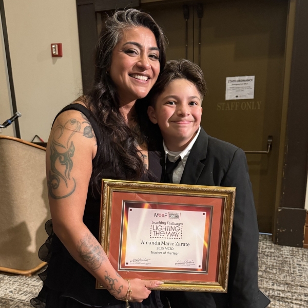 Amanda Zarate with her son Liam, holding up a framed Teacher of the Year award certificate