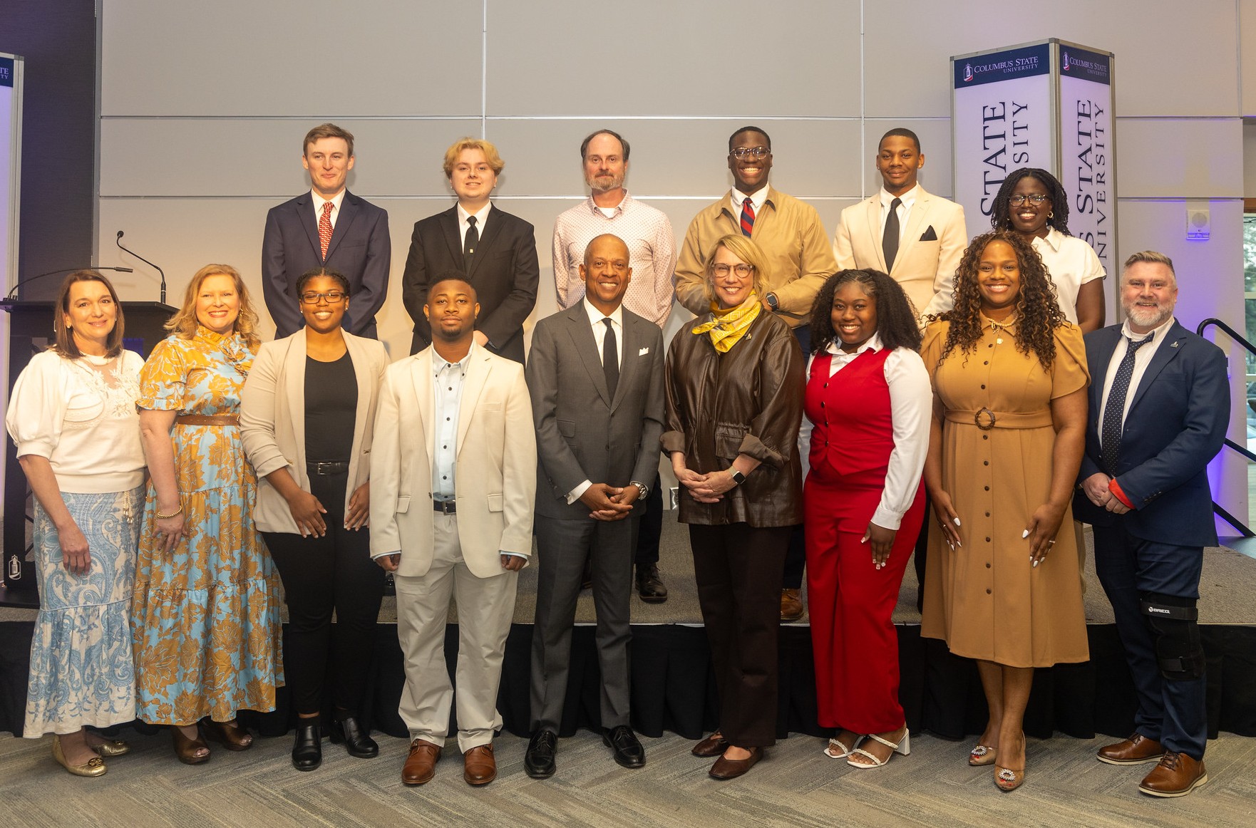Group photo of the 2026 Legacy Award recipients and university officials standing on a stage at Columbus State University.