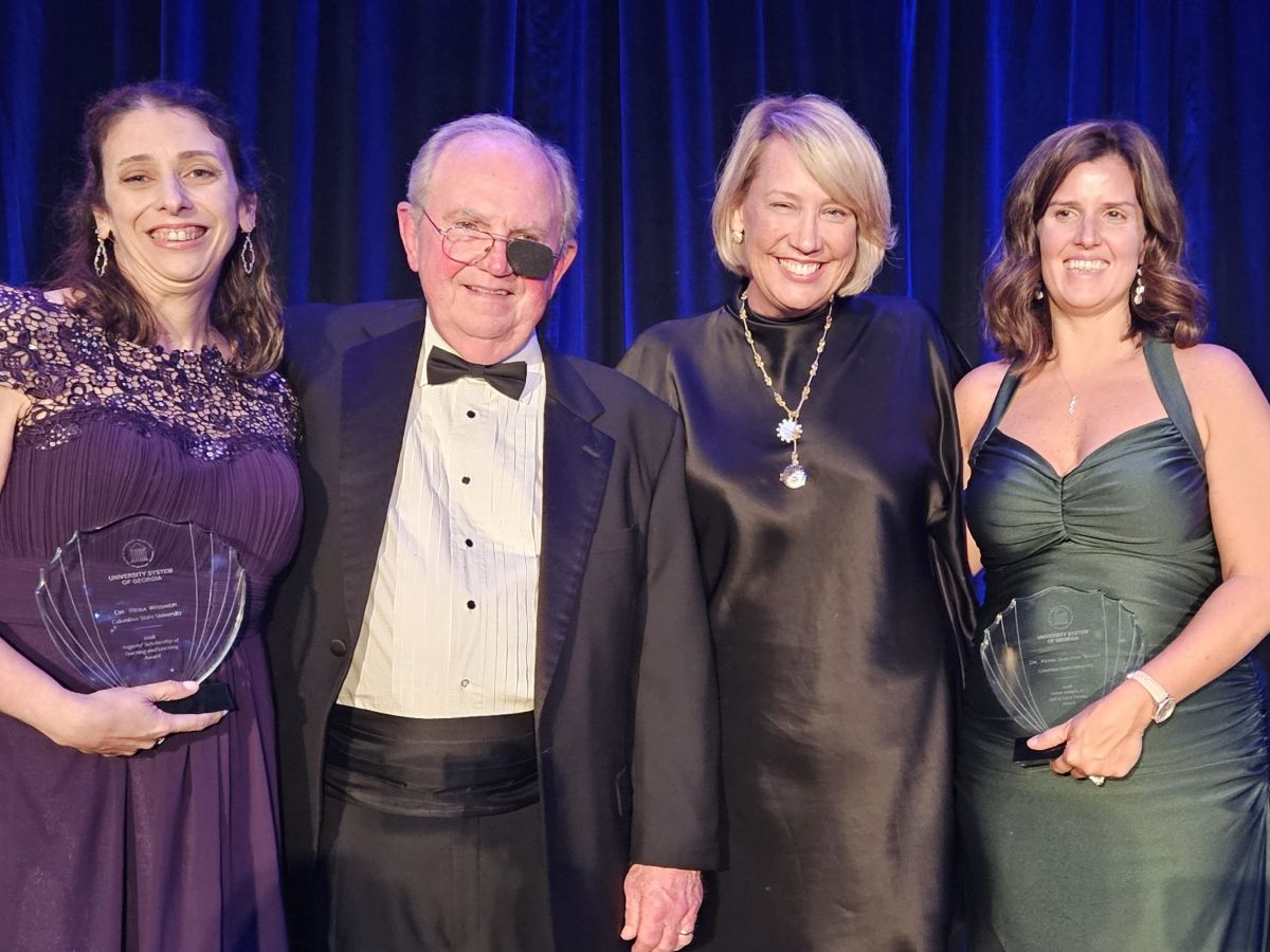 University System of Georgia award honorees pose alongside Steve Butler and CSU President Stuart Rayfield in formal evening wear at an awards gala in front of a blue backdrop.