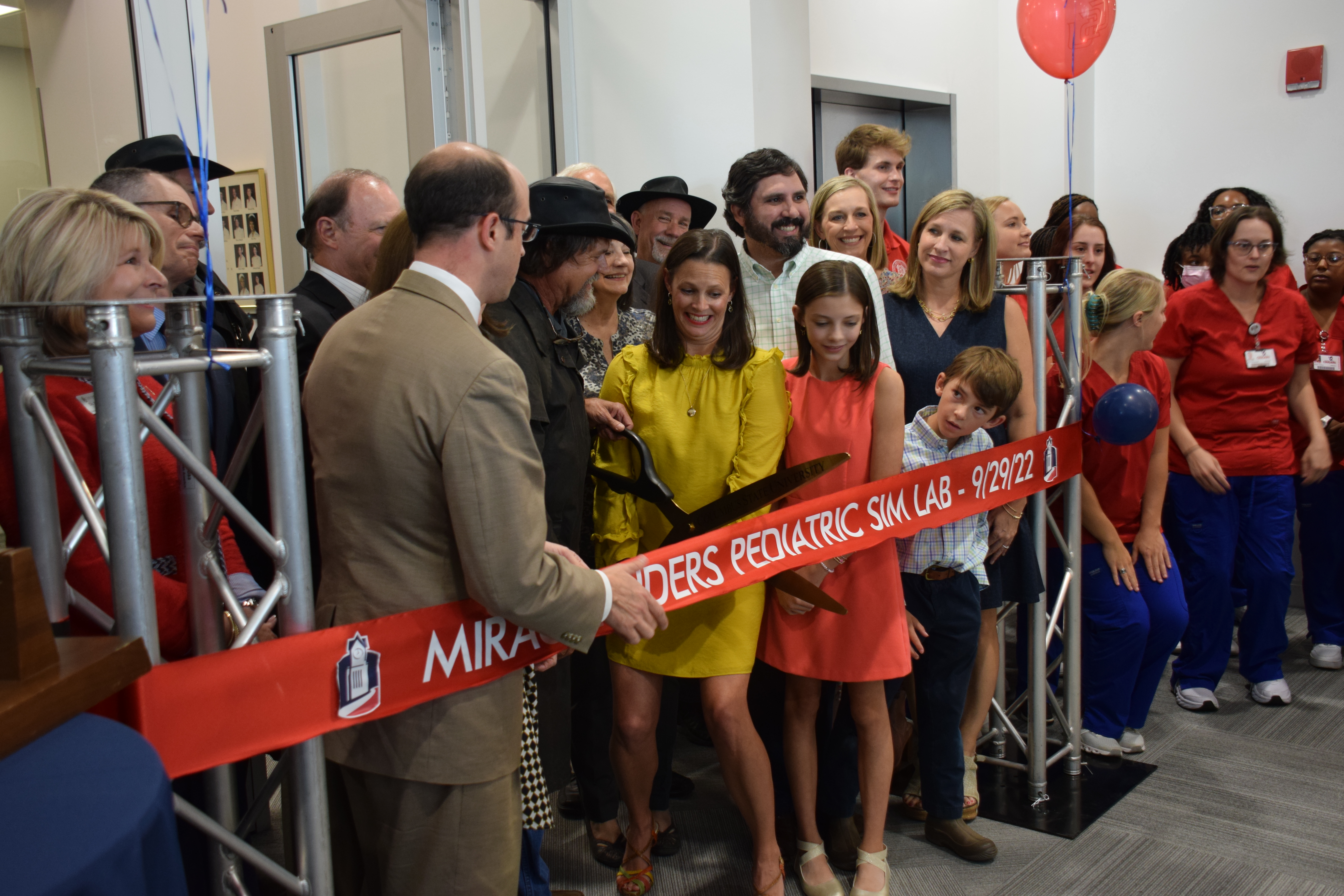 Group cutting the ribbon for the opening of the pediatric simulation lab